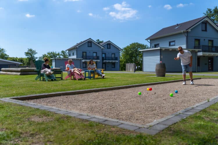 eine Gruppe von Leuten, die in einem Hof Boccia spielen