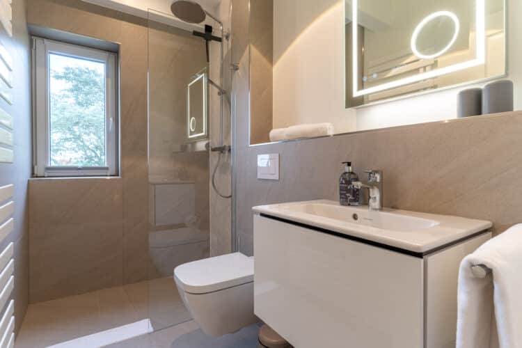 ein Badezimmer mit einer Glastür in der Dusche und einem Waschbecken